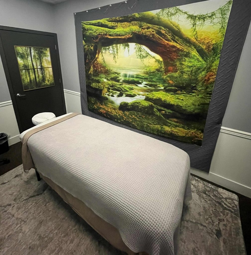 a room with a massage table and a serene forest photo